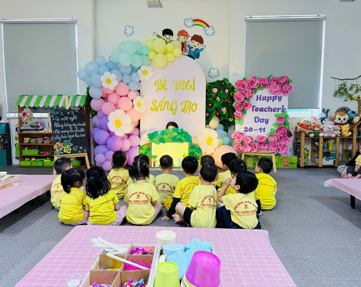 A group of children sitting on the floor in front of a stage with balloons

AI-generated content may be incorrect.